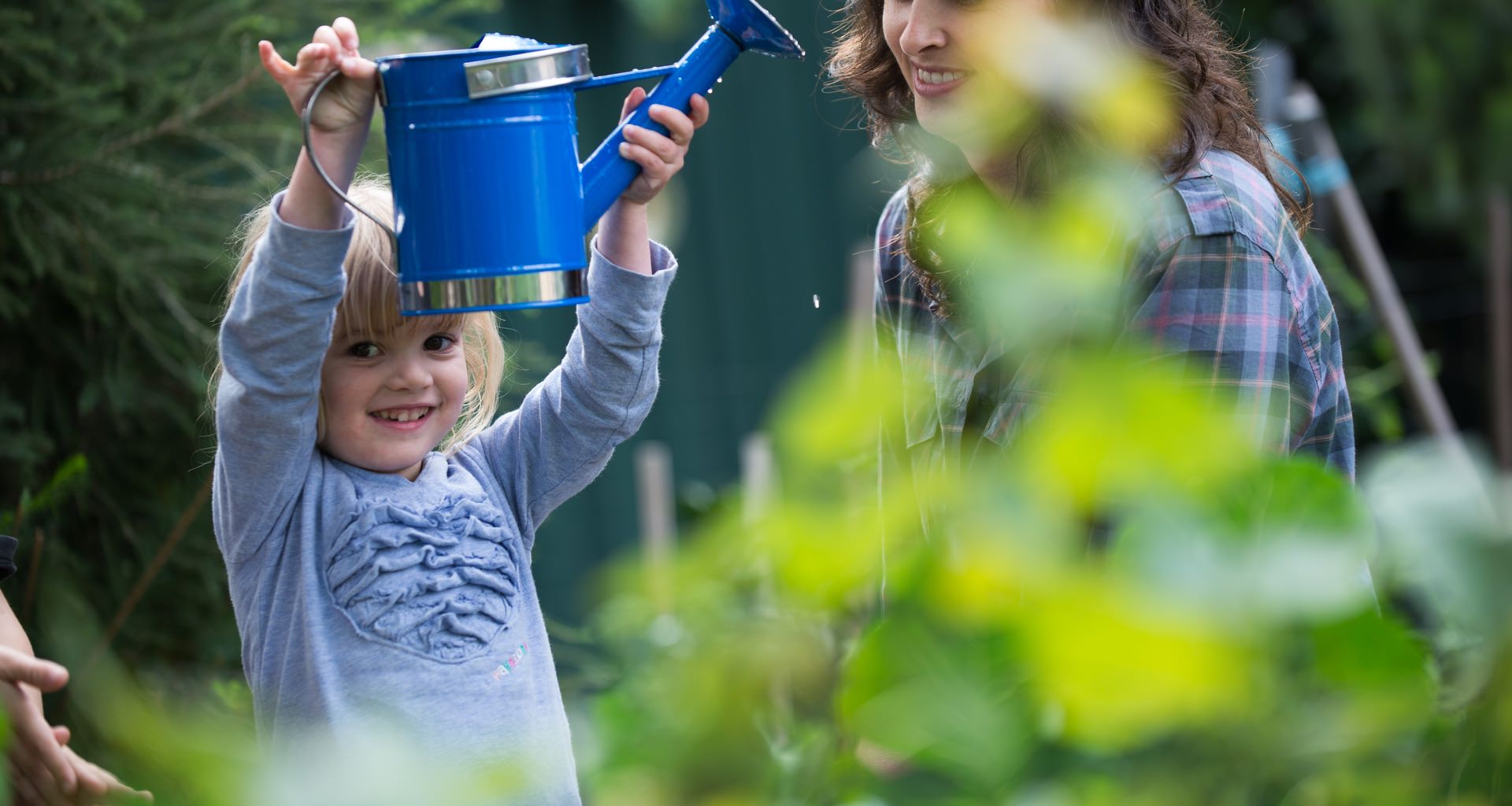 Young Girl Holding A Watering Can In Home Garden